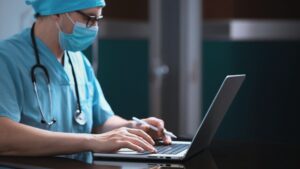 Medical professional sitting down on a laptop.