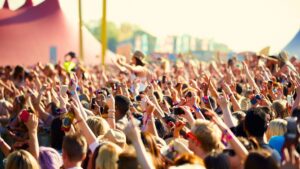A crowd near the stage at a music festival, with many arms up in the air.