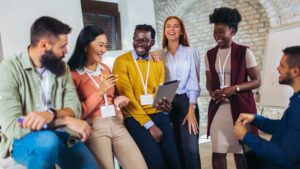 A diverse group of co-workers talk and laugh while facing the camera.