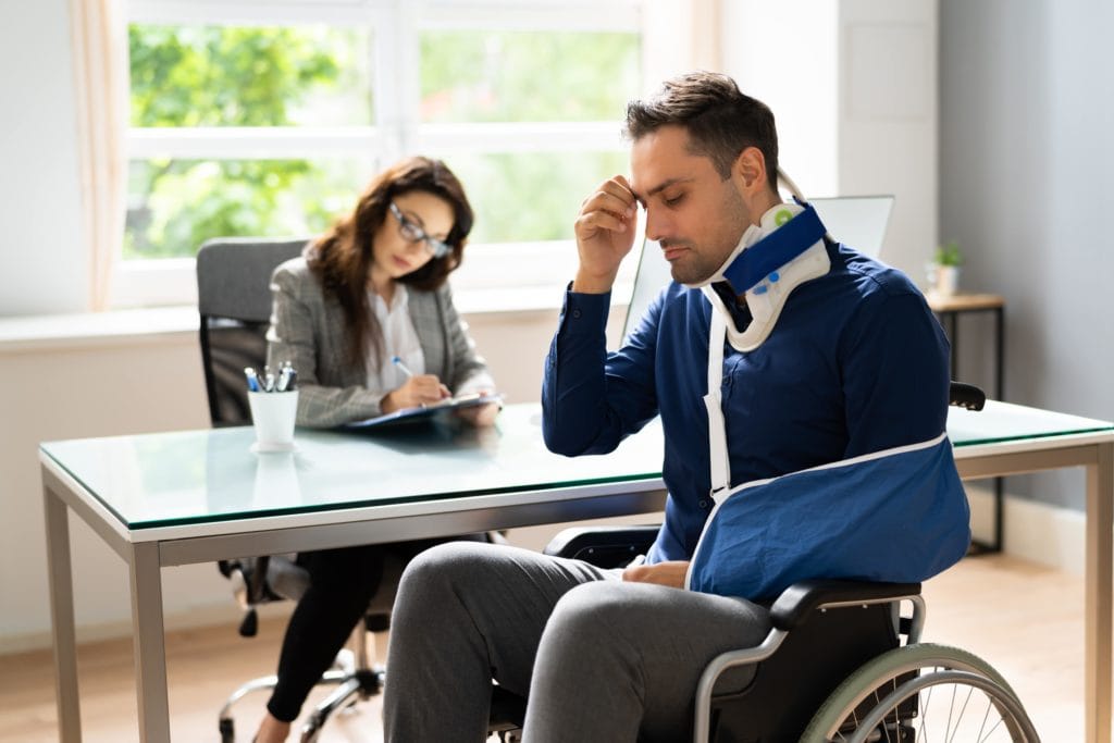 injured man in wheelchair frustrated and talking to a lawyer