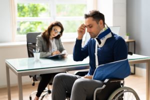 injured man in wheelchair frustrated and talking to a lawyer